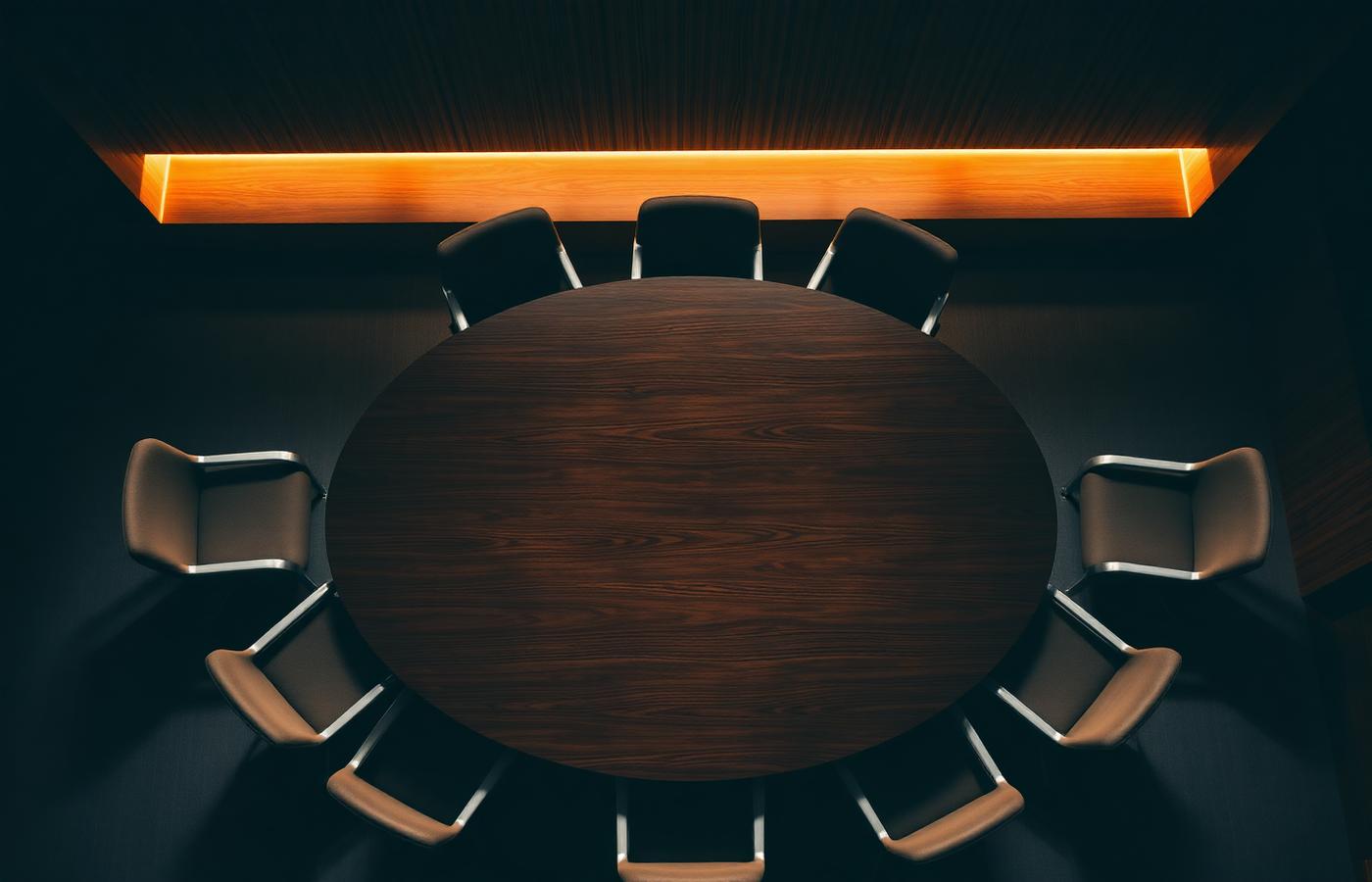 Overhead view of an empty round boardroom table under warm light